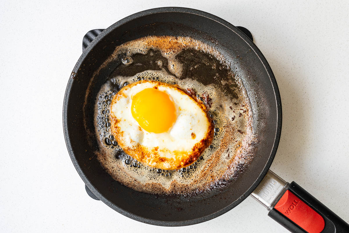 A fried egg in a small nonstick pan with butter, sesame oil and soy sauce.