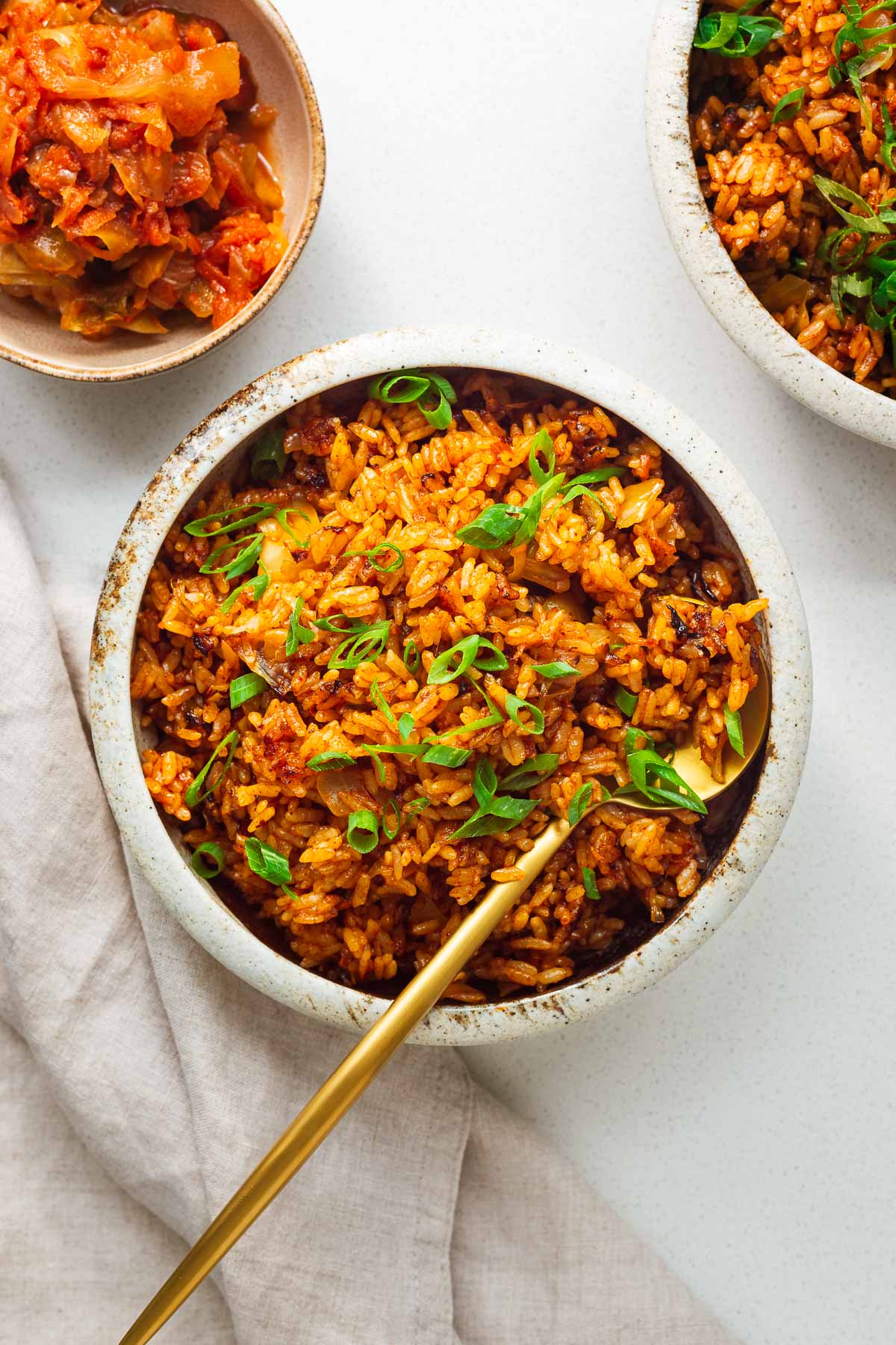 A bowl of gochujang fried rice with kimchi served with a golden spoon viewed from above.