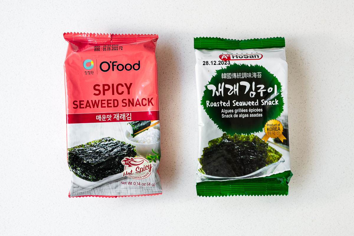 Two different packets of Korean roasted seaweed, a spicy one and a plain salted one.