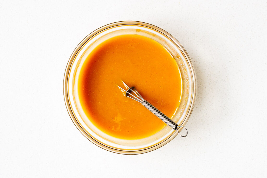 Hot honey mustard sauce mixed with a small wire whisk.