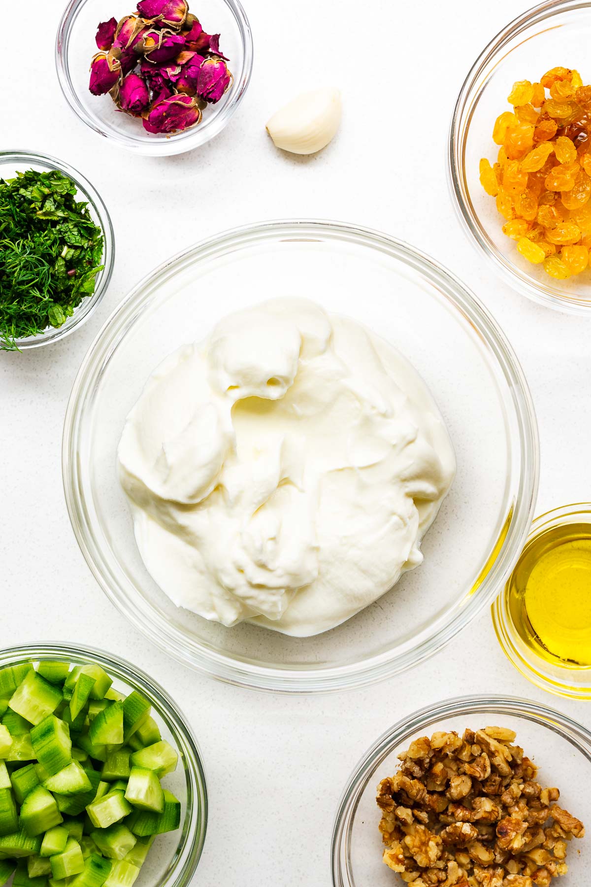Ingredients for Persian cucumber yoghurt in small glass bowls viewed from above.