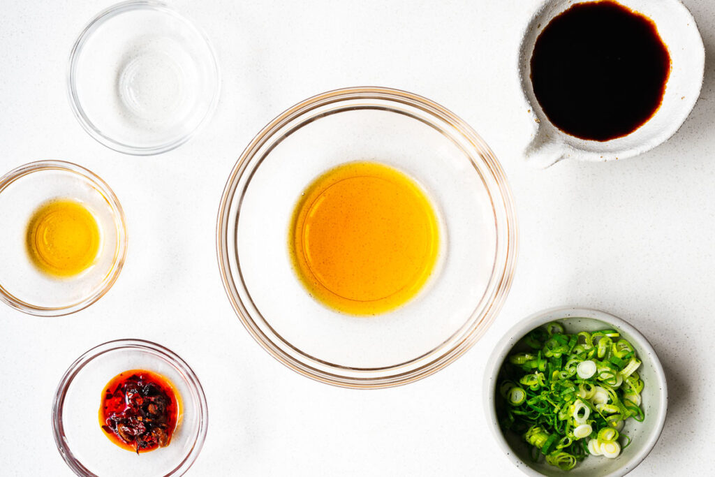 All the ingredients for a spicy soy dressing for silken tofu arranged in small glass bowls and viewed from above.