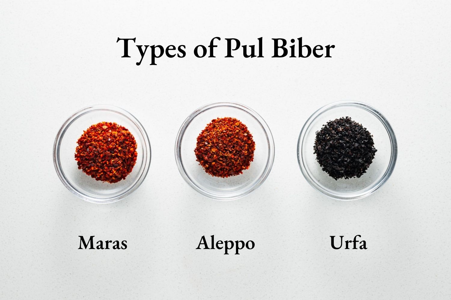 Three glass bowls with three different types of pul biber. From left there is Maras biber, Aleppo pepper and urfa biber.