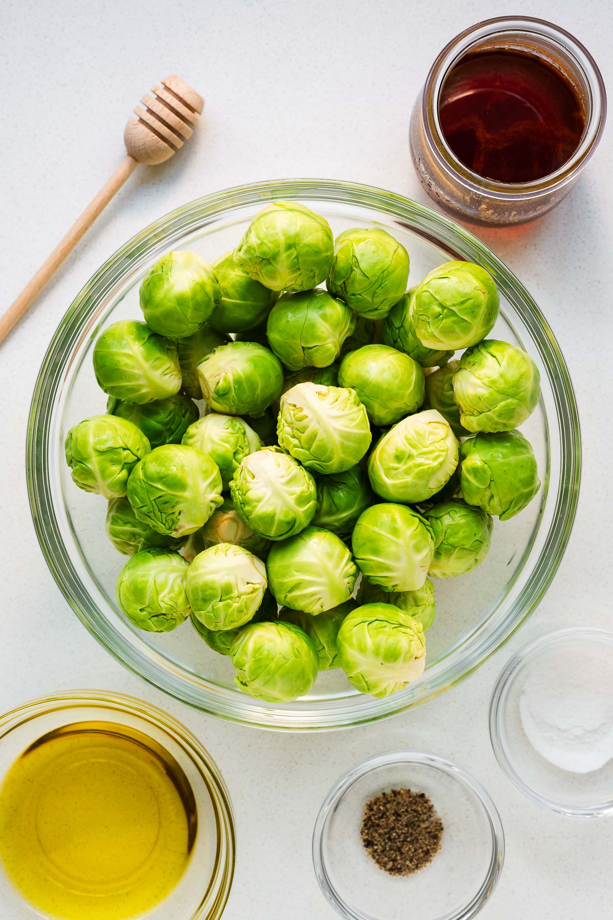 Hot honey Brussels sprouts ingredients arranged in glass bowls and viewed from above.