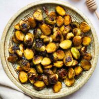 Hot honey roasted Brussels sprouts on a ceramic serving plate viewed from above.