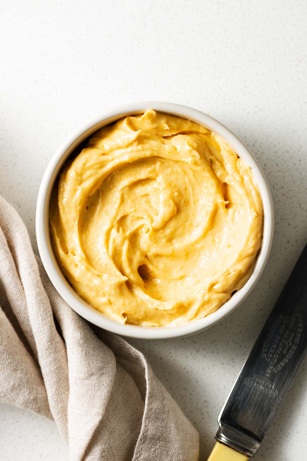 A small ceramic bowl with miso butter next to a butter knife.