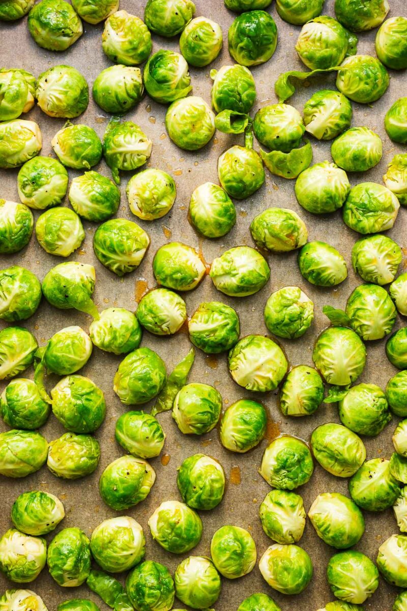 Raw Brussels sprouts halves coated in a honey glaze viewed from above.