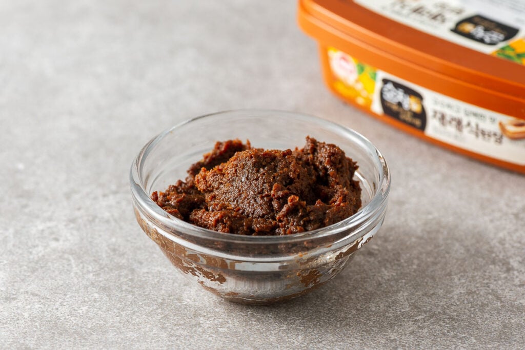 Doenjang in a small glass bowl with a deep brown colour.