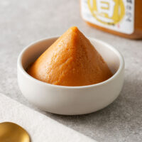 A pyramid of white miso paste in a small white bowl.