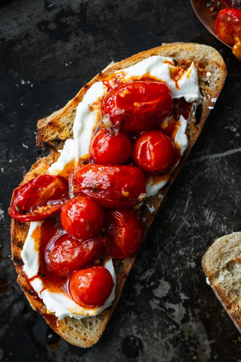 A slice of sourdough topped with glossy rose harissa tomatoes and labneh.