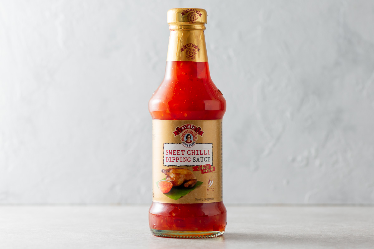 A bottle of Thai sweet chilli sauce against a grey background.
