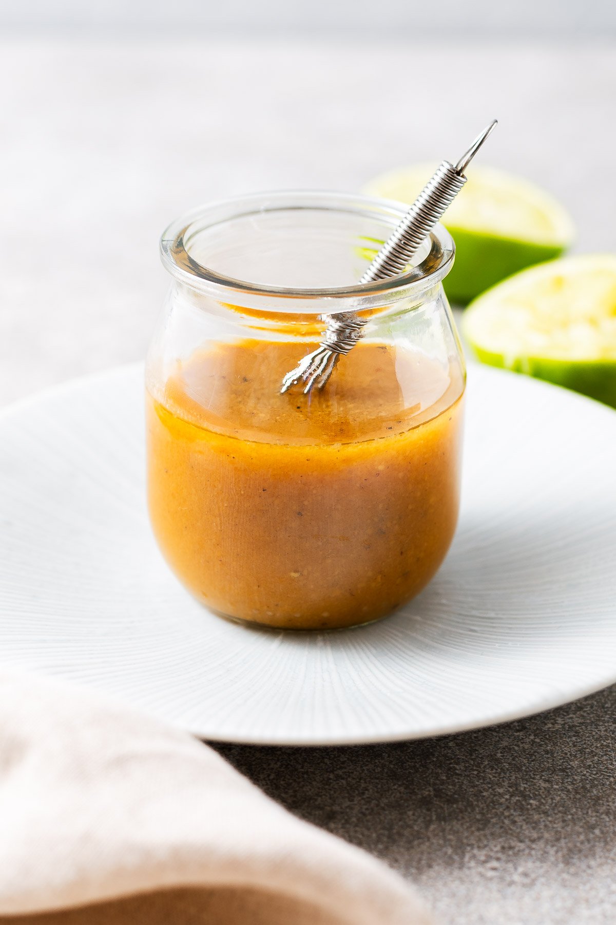 Miso lime vinaigrette in a small glass jar with a tiny metal whisk.