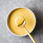 Golden miso mayo is scooped with a small teaspoon. The creamy mayonnaise coats the teaspoon.