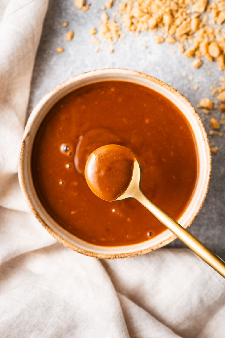 A spoonful of hoisin peanut sauce scooped from a small bowl.