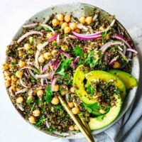 Kale quinoa chickpea salad topped with avocado and a lemon dressing.