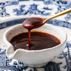 A teaspoon of homemade okonomiyaki sauce scooped from a small bowl.