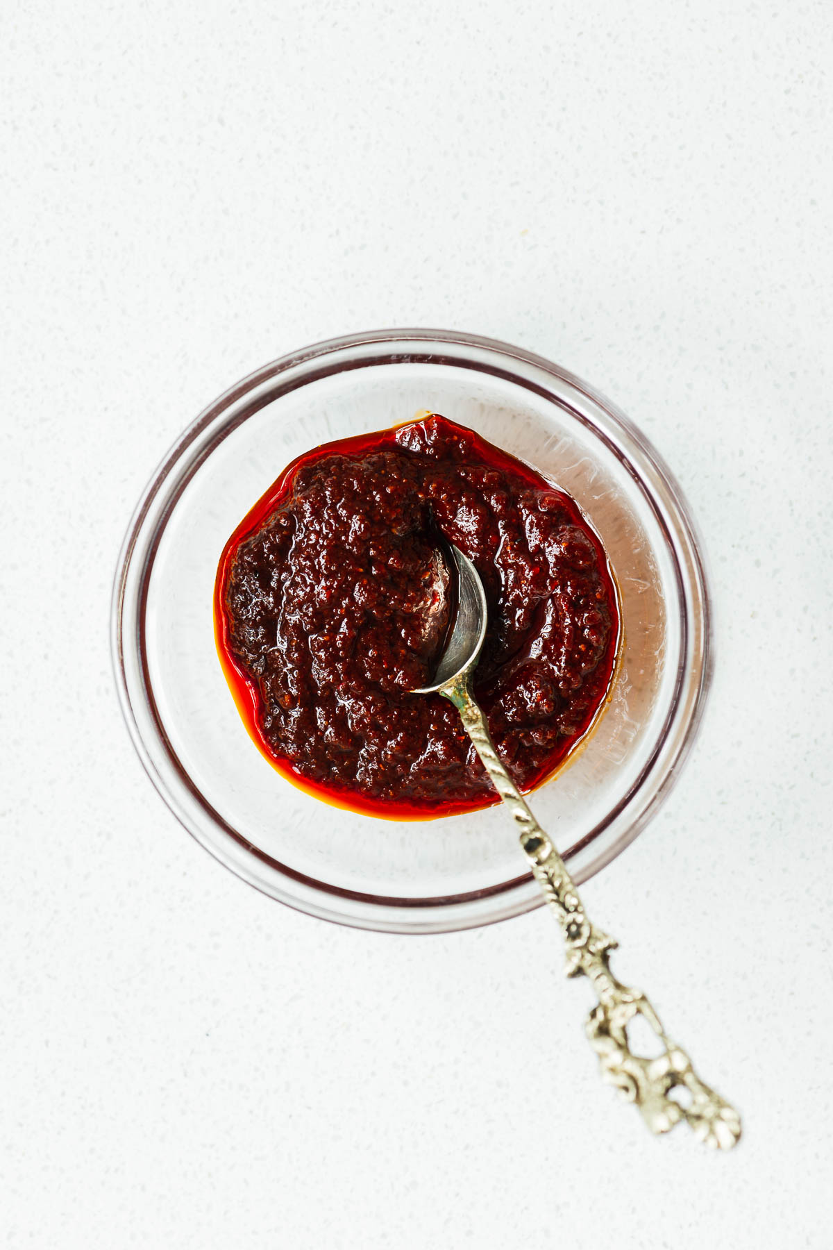 Harissa paste mixed from harissa powder, olive oil, water, lemon juice and tomato paste in a small bowl. It is a thick and glossy paste.
