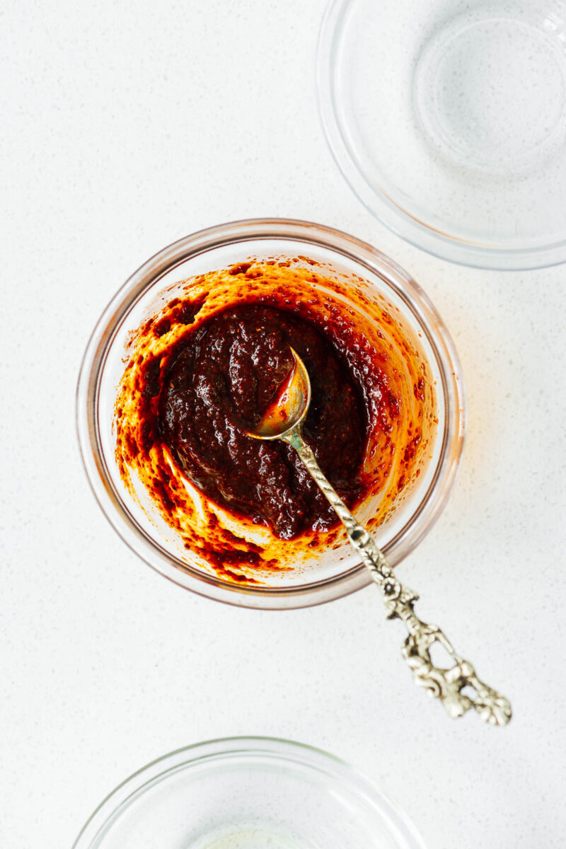 Rehydrated harissa powder mixed with oil and lemon juice in a small bowl. The paste has a thick consistency.