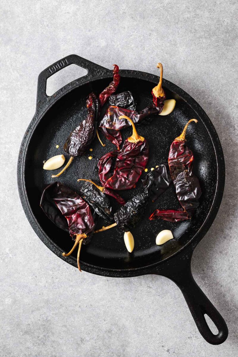Dried chile peppers and fresh garlic cloves in a cast iron skillet.