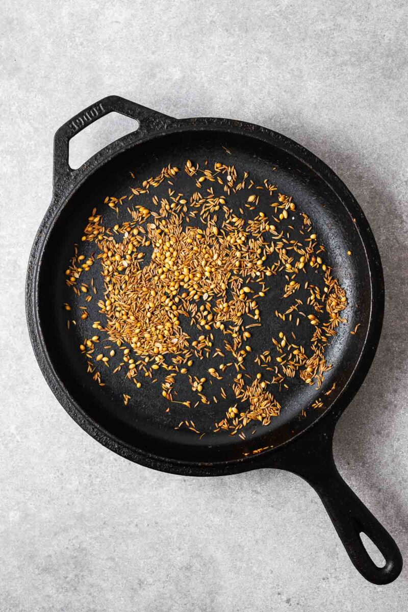 Toasted cumin, coriander and caraway seeds in a cast iron skillet.