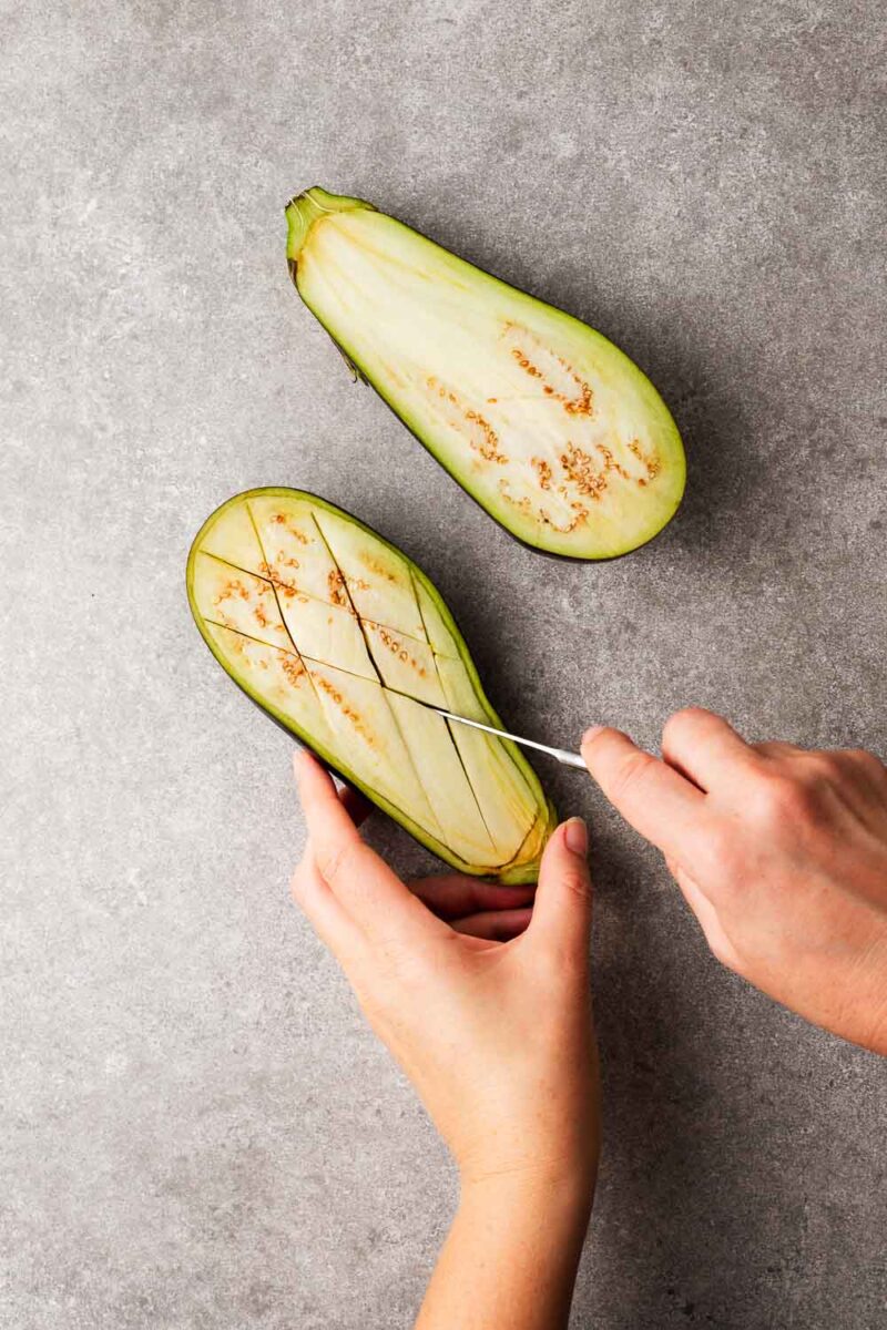 Creating parallel slices in the eggplant without cutting all the way through.