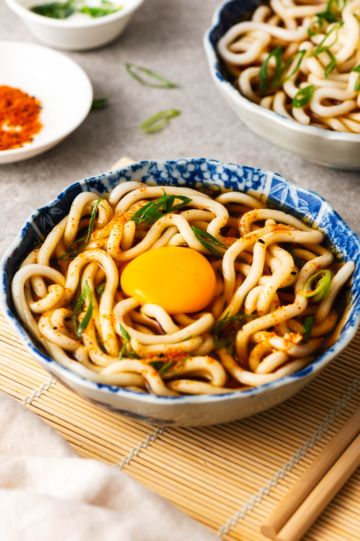 A Japanese ceramic bowl with moon viewing noodles, a raw egg yolk nestled into the noodles resembles the full moon.