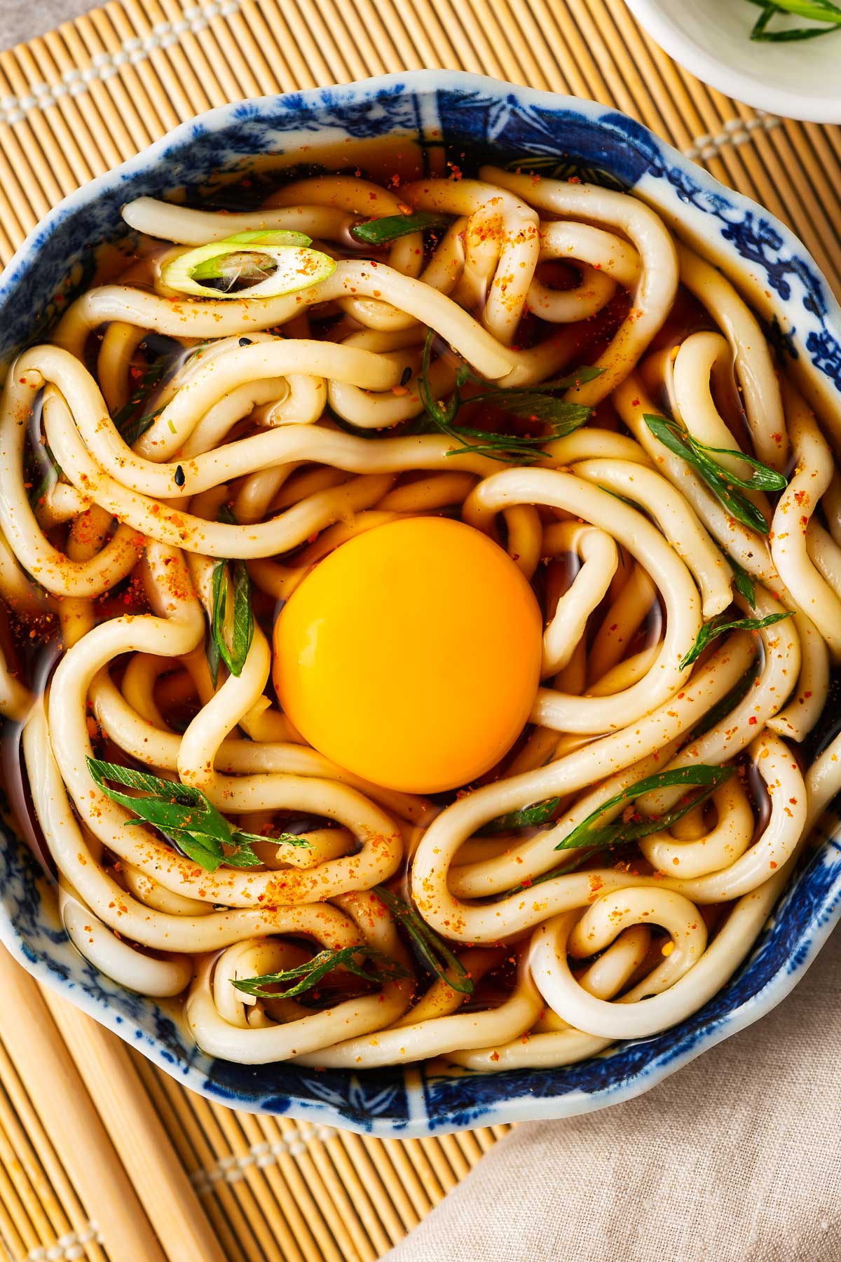 A raw egg yolk nestled into udon noodle soup.