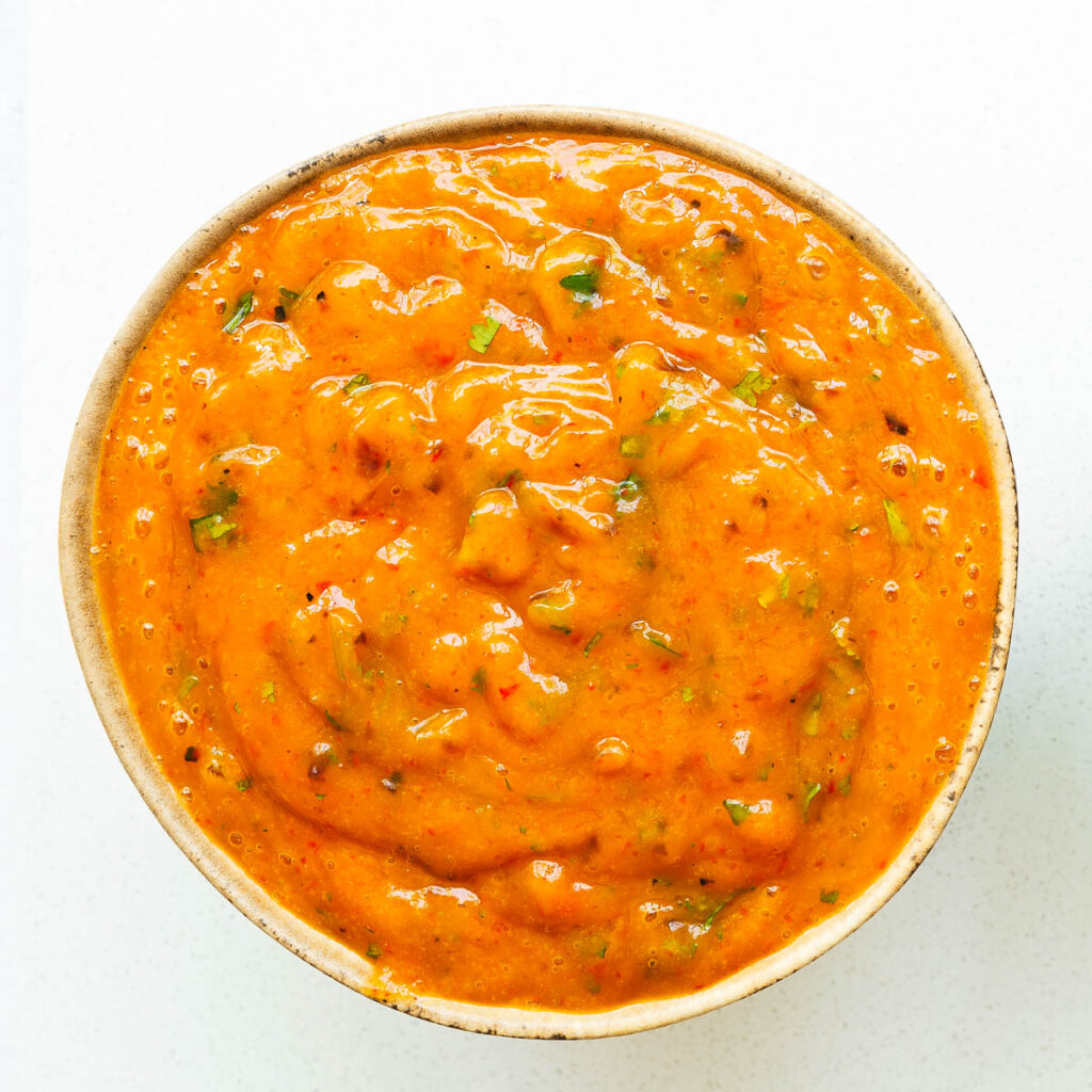 A bowl of vibrant orange roasted mango salsa with a smooth consistency.