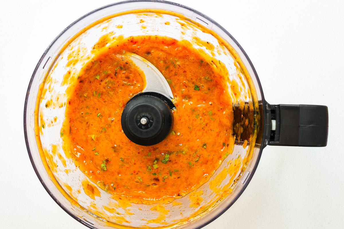 Spicy roasted mango salsa in a food processor with a smooth sauce-like consistency.