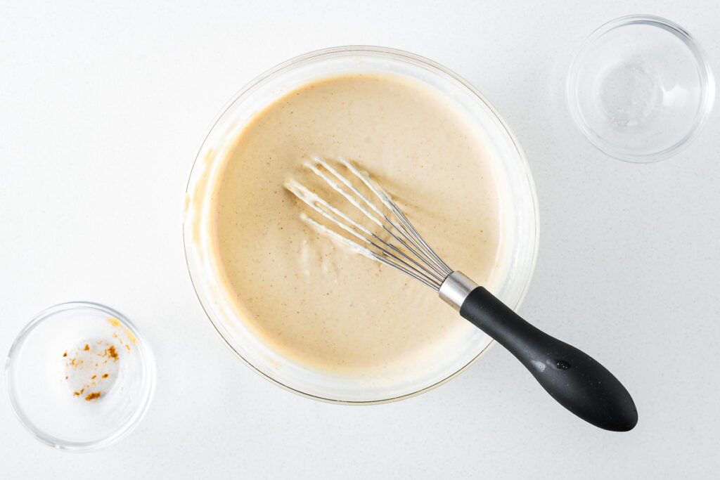 Easy tahini sauce with a whisk in a glass bowl.