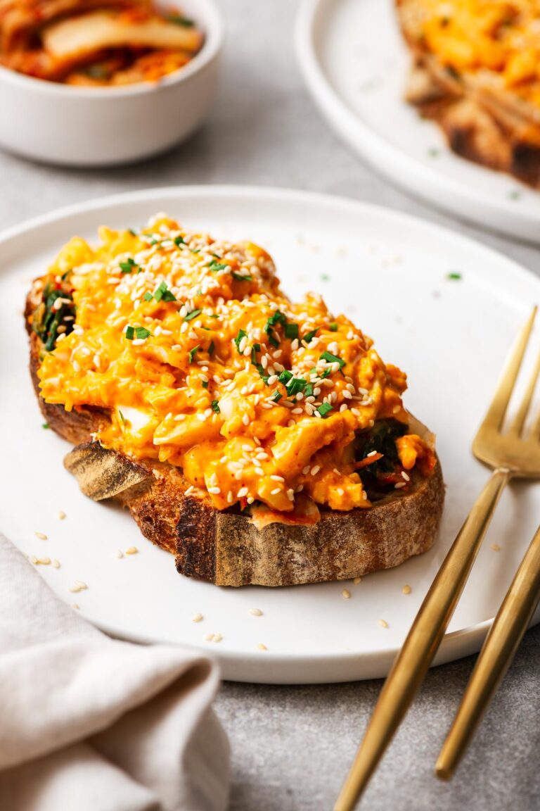Gochujang eggs on sourdough toast topped with toasted sesame seeds, chopped chives and more kimchi on the side.